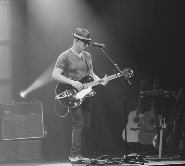 Jim Rhodes performing live on stage with guitar